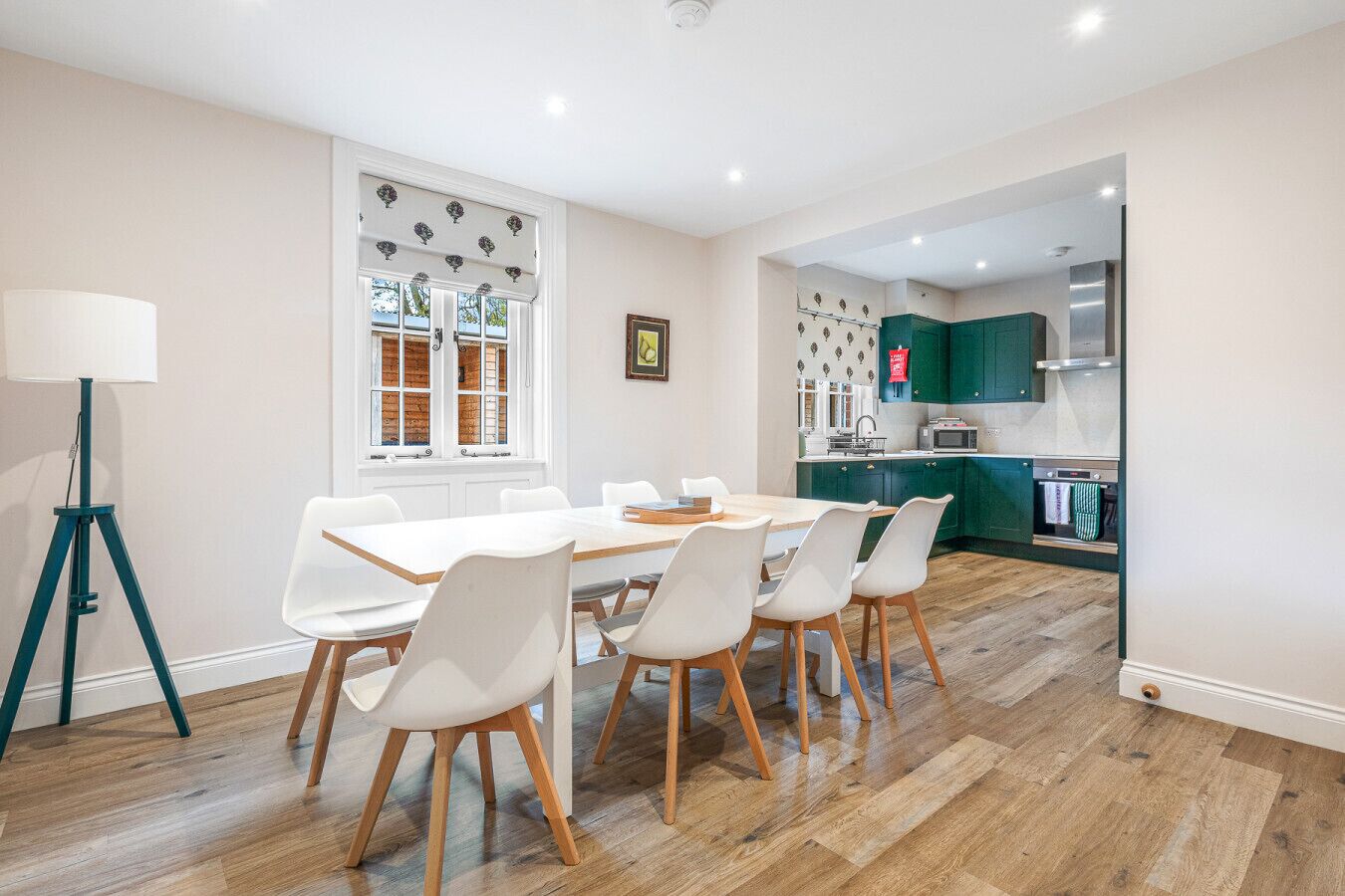 A modern kitchen with green cabinets, a white countertop, and a stainless steel range hood.