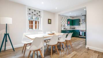 A modern kitchen with green cabinets, a white countertop, and a stainless steel range hood.
