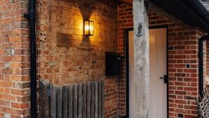 Een bakstenen gebouw met een houten hekwerk, een deur en een bordje met de tekst 'Old Town Cottage'.