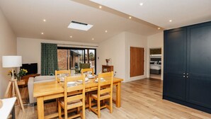 A spacious room with a wooden dining table, a large dark wardrobe, and a sliding glass door leading to a balcony.