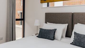 Een hotelkamer met een bed, nachtkastje, lamp en raam met gordijnen.