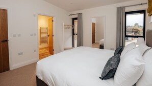 A hotel room with a large bed, a wardrobe, a mirror, and a window with a view.