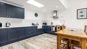 A modern kitchen with dark blue cabinets, a wooden dining table, and a large window.