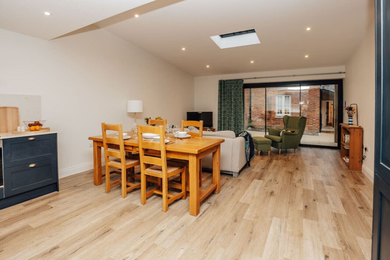 Una sala de estar moderna con una mesa de comedor de madera, un sofá y una televisión.