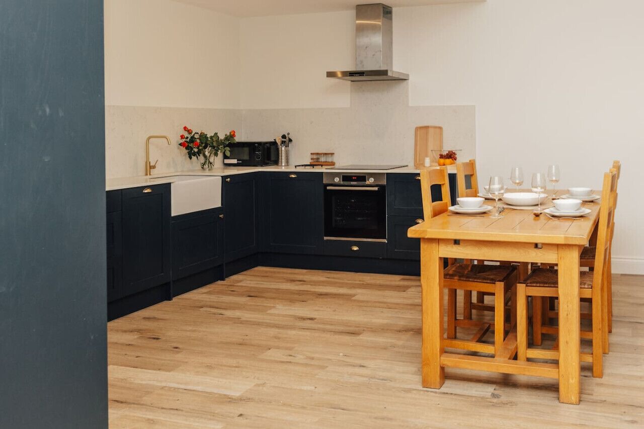 Una cucina moderna con pensili scuri, un tavolo da pranzo in legno e un forno integrato.