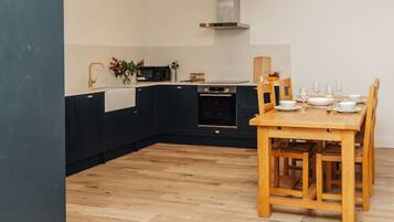 Una cucina moderna con pensili scuri, un tavolo da pranzo in legno e un forno integrato.