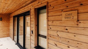 A wooden interior with a sign reading "CART SHED 2" and a door leading to another room.