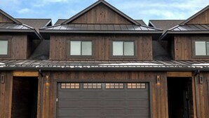 Una casa a due piani in legno con un'ala garage scura, due finestre al piano superiore e il numero '701' ben visibile sulla porta del garage.