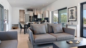 A modern living room with a grey sofa, a dining area, and a kitchen in the background. - Apartment 'Drys Il' with Sea View, Wi-Fi and Air Conditioning (Ellinika)