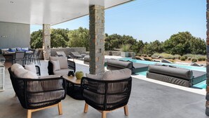 An outdoor patio with wicker furniture, a pool, and stone pillars. - Apartment 'Drys Il' with Sea View, Wi-Fi and Air Conditioning (Ellinika)