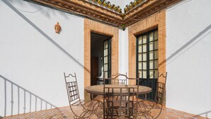 A patio with a round table and chairs, a brick wall, and a window with a view.