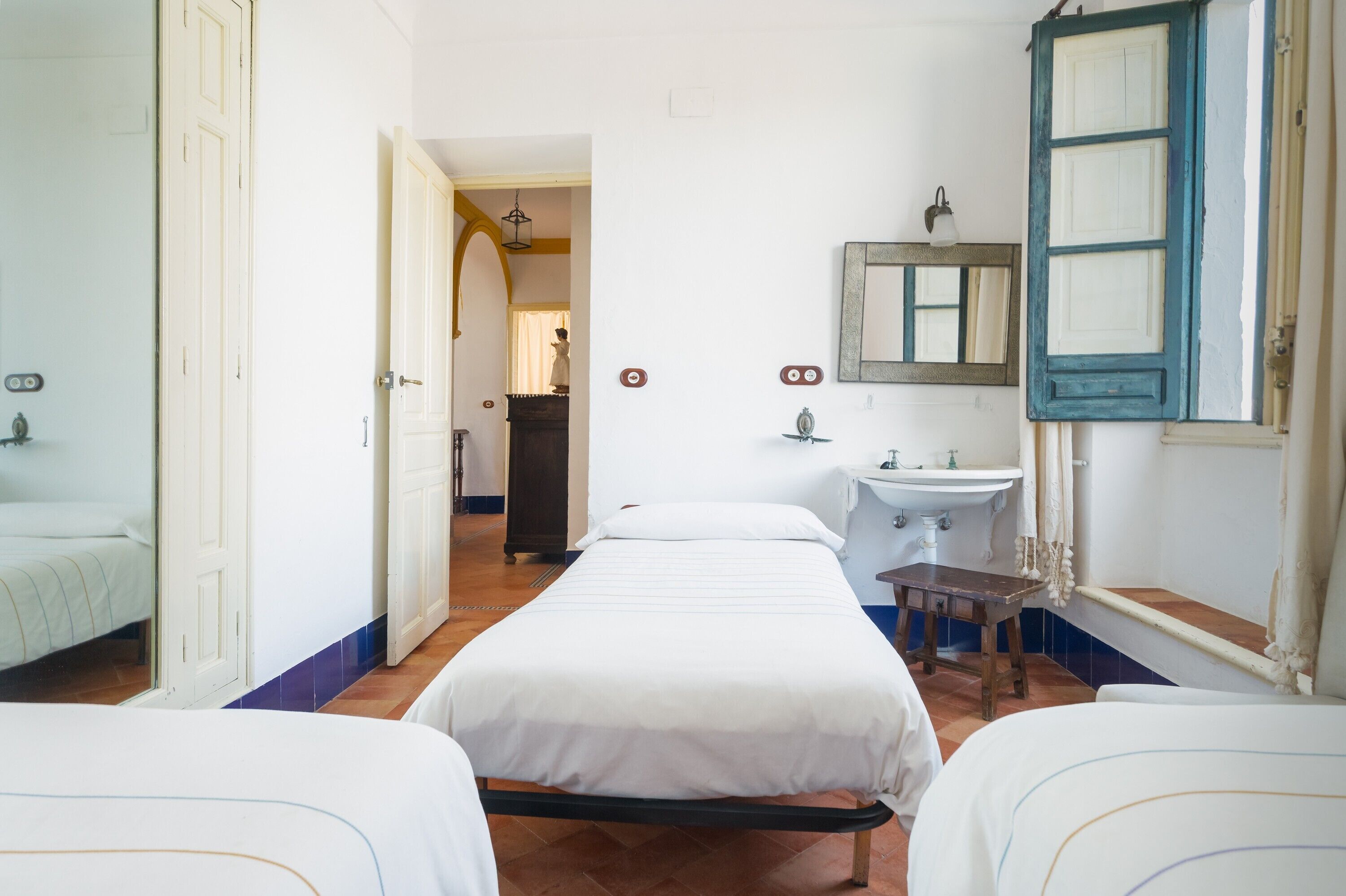 Una habitació d'hotel amb un llit, una taula de nit, un mirall, un lavabo i una porta.
