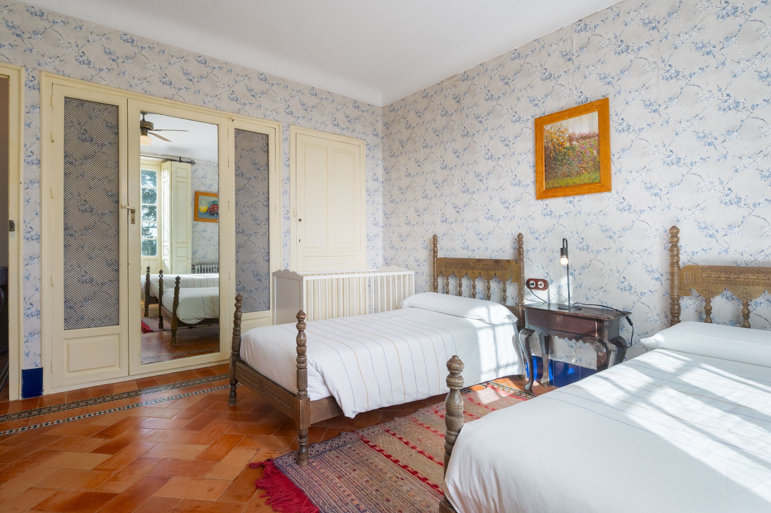 A bedroom with a double bed, a bedside table, a mirror, a radiator, and a wardrobe with a mirror.