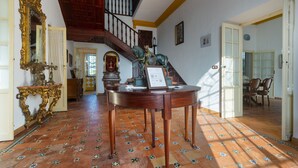 A grand room with a staircase, a round wooden table, and a decorative mirror.