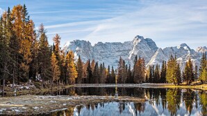A mountain landscape with a lake reflecting trees and mountains. - Studio 'Dolomiti E Misurina My Dreams' with Lake View and Balcony (Auronzo di Cadore)