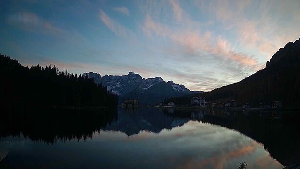 Un lac paisible qui reflète les montagnes et un bâtiment à étages.