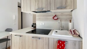 A modern kitchen with a built-in stove, a sink, and wooden cabinets. - Studio 'Dolomiti E Misurina My Dreams' with Lake View and Balcony (Auronzo di Cadore)