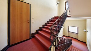 A staircase with red carpeted steps and a wooden door. - Studio 'Dolomiti E Misurina My Dreams' with Lake View and Balcony (Auronzo di Cadore)