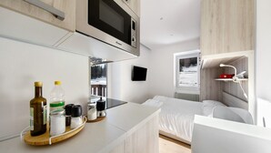A modern kitchen with a microwave, a wooden countertop, and a bed with a view of the outdoors. - Studio 'Dolomiti E Misurina My Dreams' with Lake View and Balcony (Auronzo di Cadore)