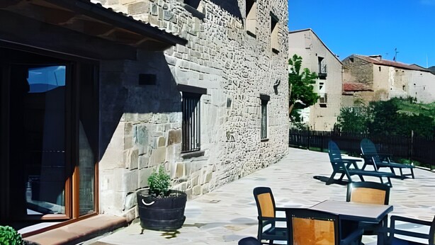 Un edificio in pietra con patio e area salotto all'aperto, arredata con piante in vaso.