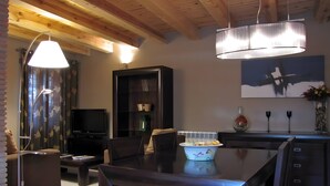 A modern living room with a dark wooden dining table, comfortable seating, a television, and a bookshelf. - Spacious Country House 'El Ventorro' with Mountain Views (Bretún)
