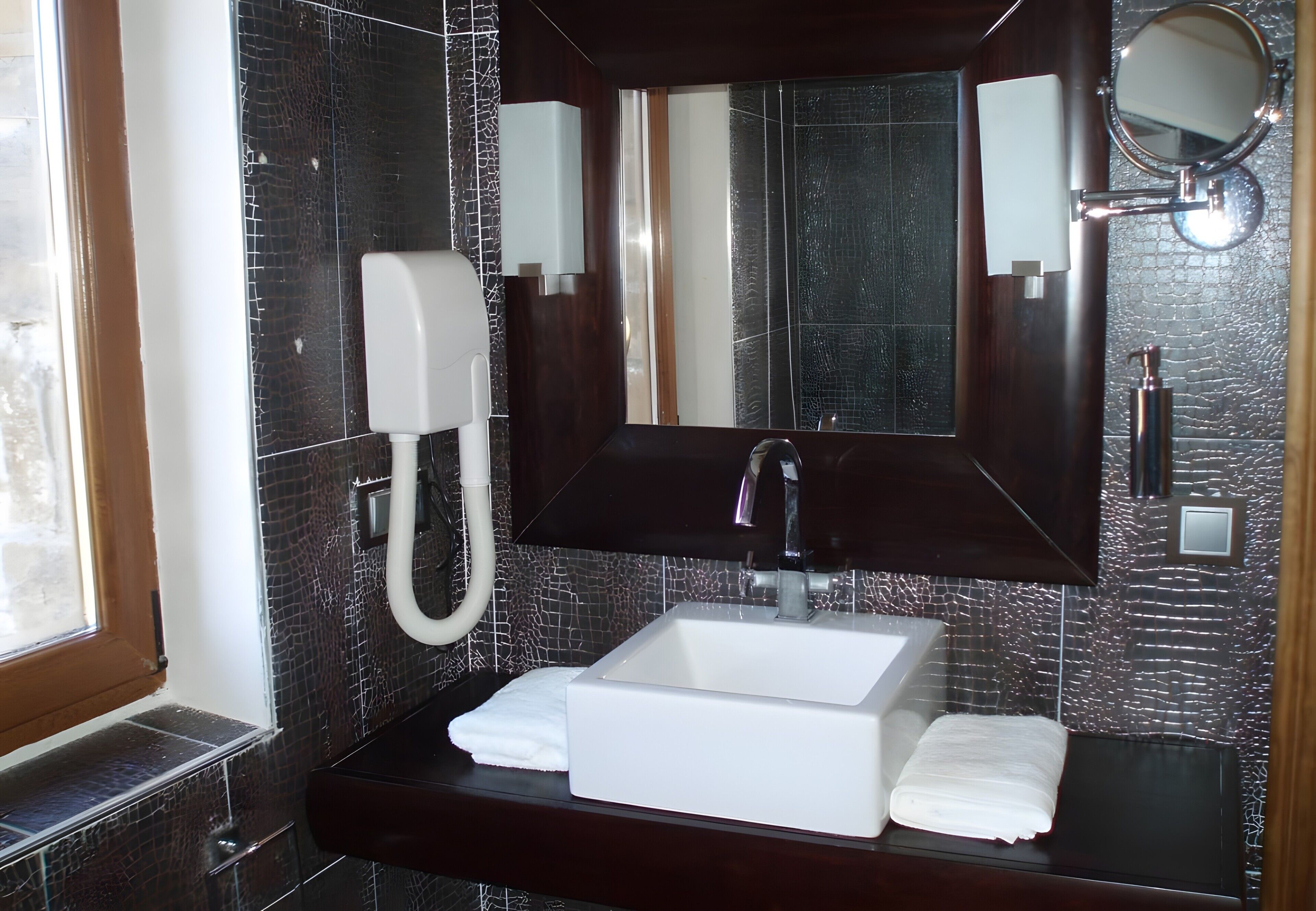 A bathroom with a white sink, a mirror, a telephone, and a towel rack.