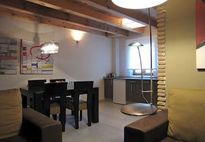 A modern kitchen with wooden beams, a dining area with a table and chairs, and a bright pendant light.