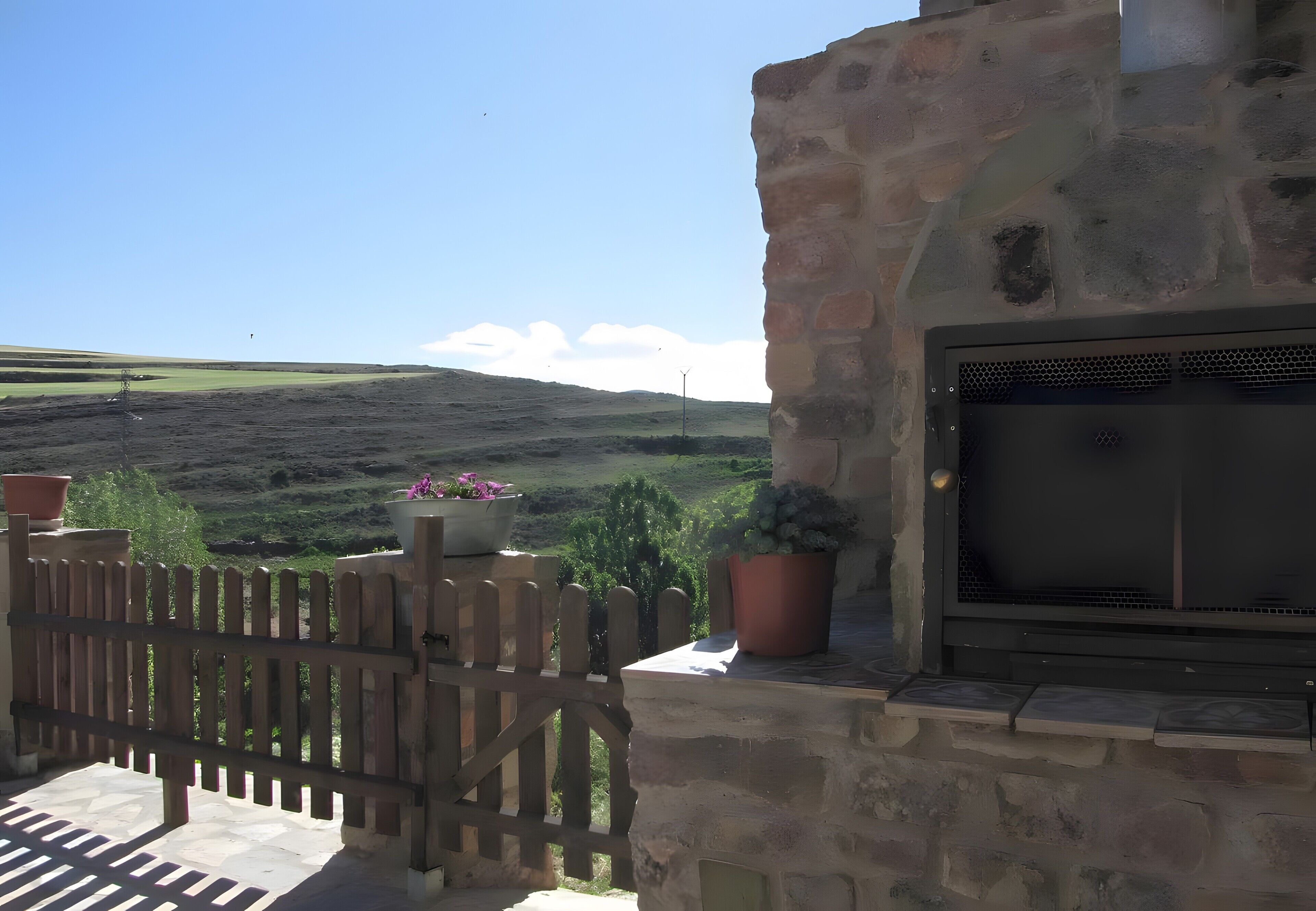 A stone building with a grill and potted plants.
