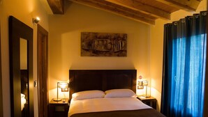 A hotel room with a large bed, two bedside lamps, a wooden headboard, a painting on the wall, and a window with curtains. - Cosy Countryside Retreat 'Las Rozas' with Mountain Views (Bretún)