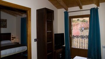 Une chambre à coucher avec un lit, une télévision, une armoire en bois et une fenêtre avec des rideaux.