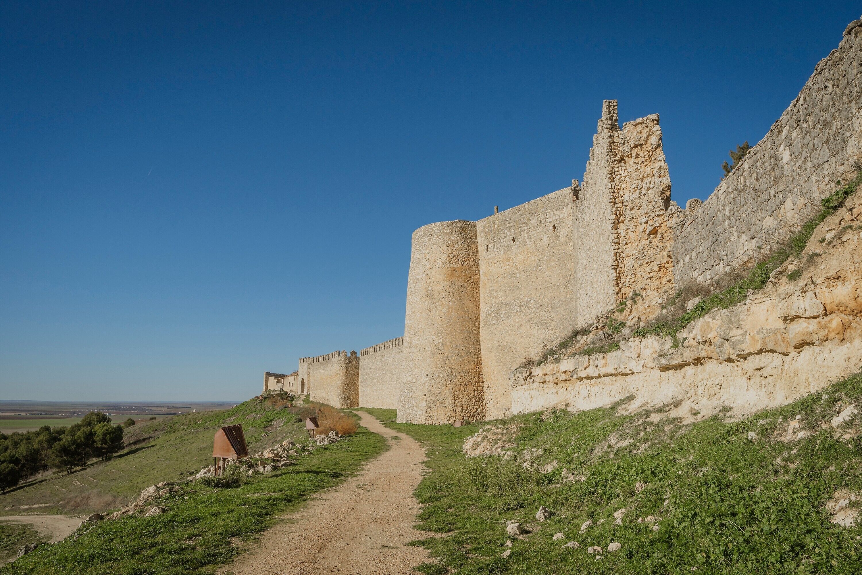 A historical stone castle with a dirt path leading to the entrance.