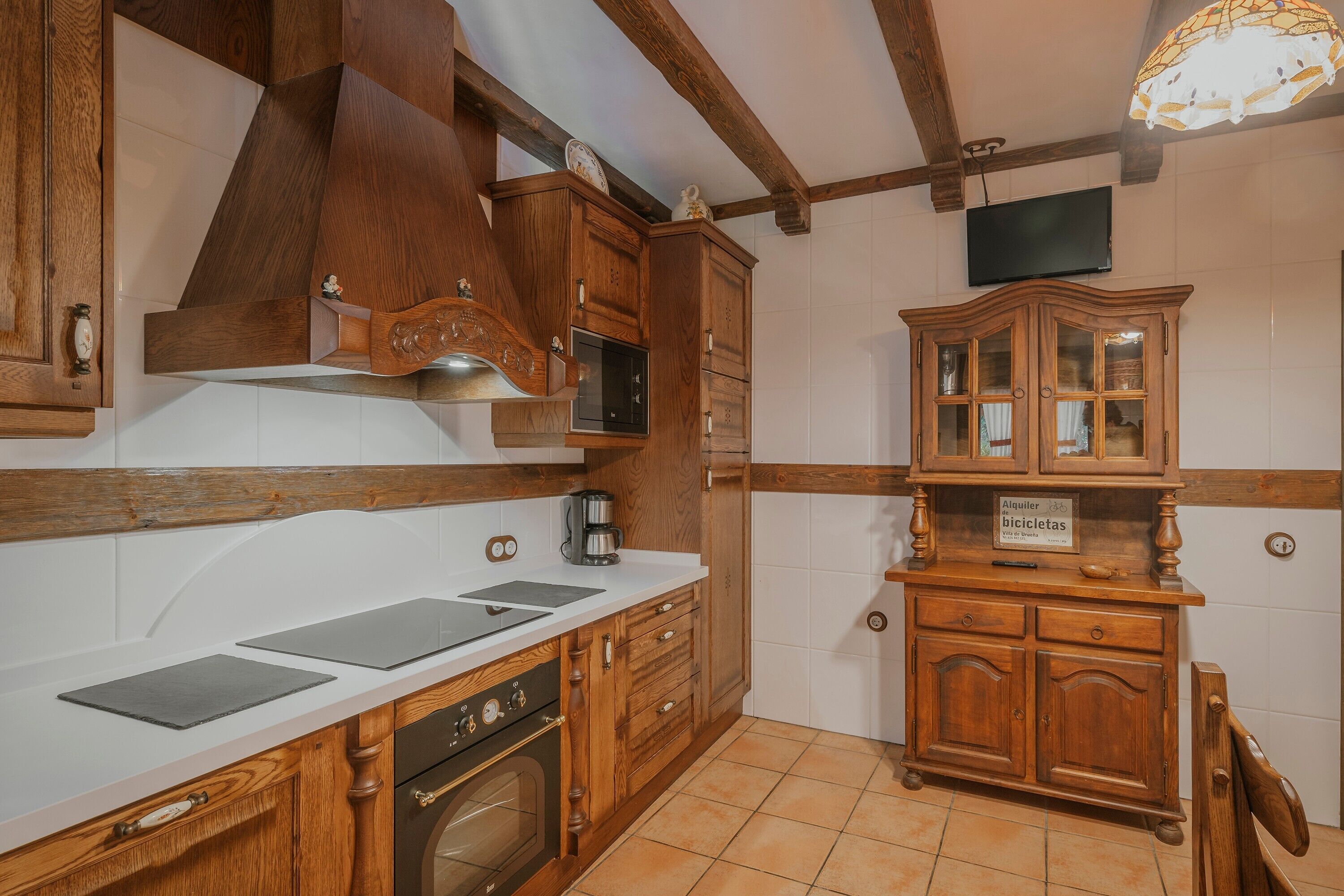 A kitchen with wooden cabinets, a microwave, a coffee maker, and a sign indicating a bicycle rental service.