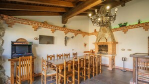 Un coin repas avec une cheminée en briques, des chaises en bois, une table en bois et un téléviseur.