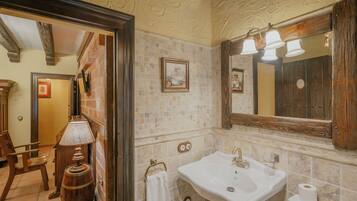 Un baño con lavamanos, espejo y un barril de madera.