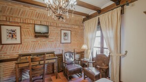 Um quarto com parede de tijolos, móveis de madeira, um lustre e uma televisão.