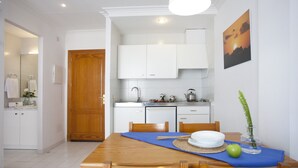 Een moderne keuken met witte kastjes, een houten eettafel en een blauwe placemat.