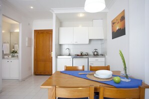 Una cocina moderna con armarios blancos, una mesa de comedor de madera y un camino de mesa azul.