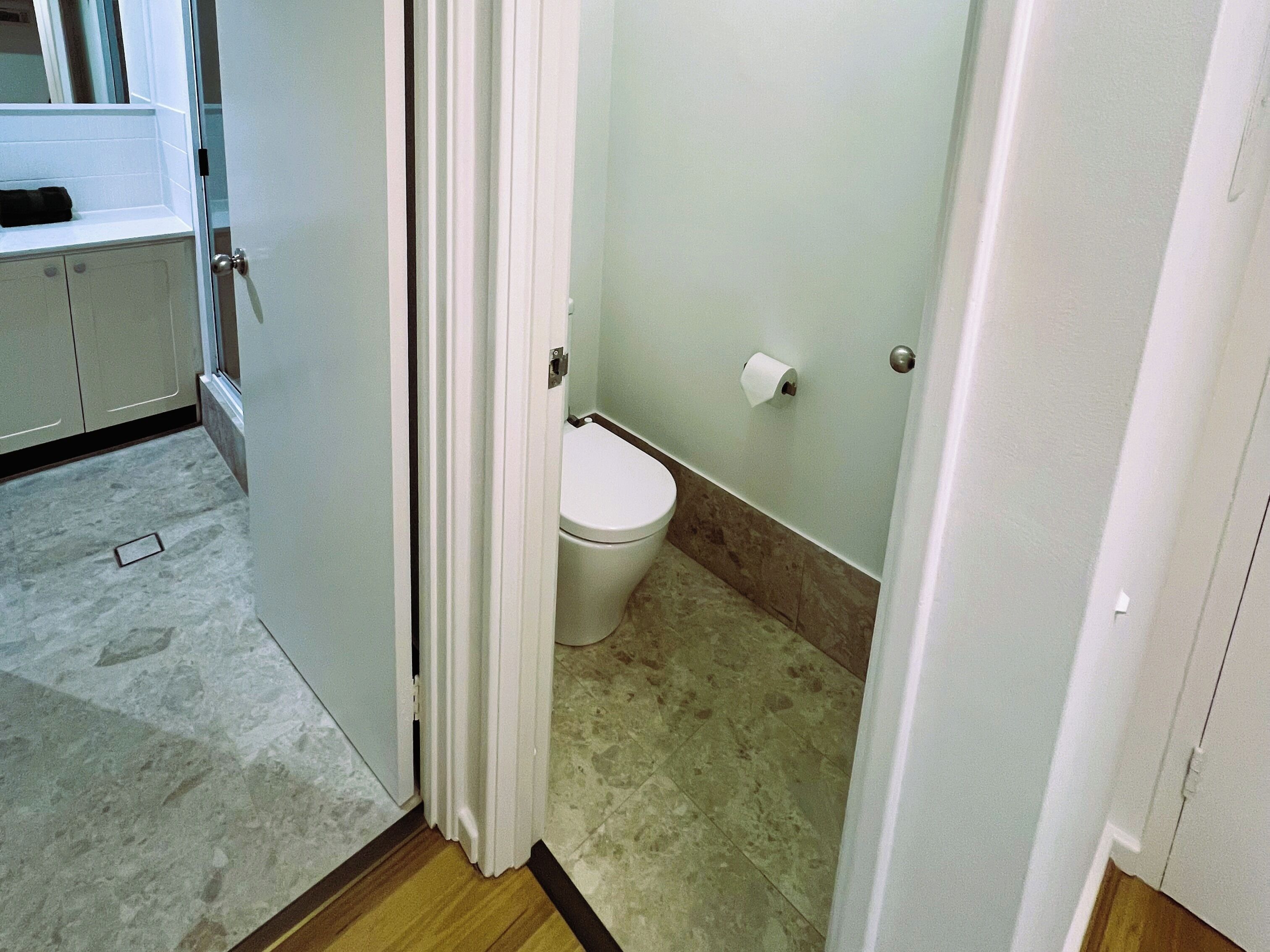 A bathroom with a toilet, a roll of toilet paper, and a shower area.