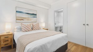 Quarto com cama, mesas de cabeceira, um guarda-roupa e um quadro na parede.