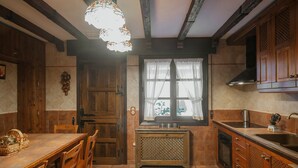 A kitchen with wooden cabinets, a tiled floor, a window with curtains, and a hanging light fixture.