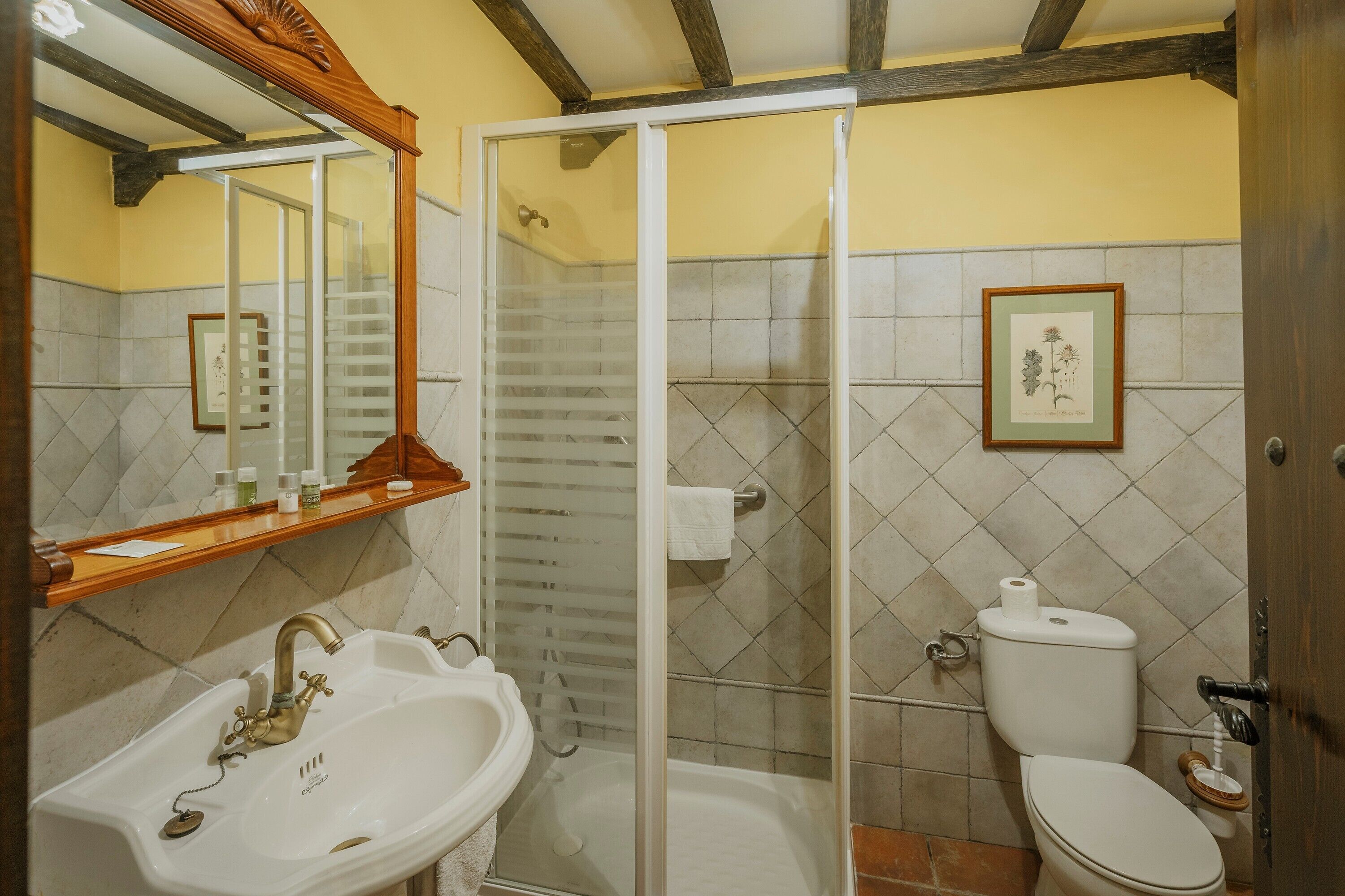 Ein Badezimmer mit Waschbecken, Toilette, Dusche und einem gerahmten Pflanzenbild an der Wand.
