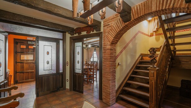 A wooden staircase with a brick archway leading to a dining area.