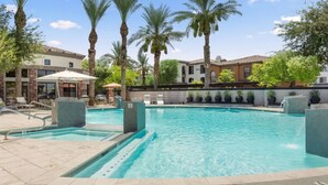 A swimming pool with a tiled deck, lounge chairs, and palm trees. - Zone LUXE (Glendale)
