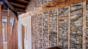 A stone wall with wooden beams, a wooden door, and a tiled floor. - Pyrénées Cottage with Mountain View, Private Terrace, and Wi-Fi – Top-Rated Accommodation (Lau-Balagnas)