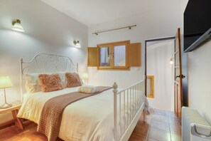 Een slaapkamer met een bed, nachtlampjes, een raam en een radiator.