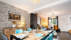 Un comedor con una mesa de madera dispuesta para cuatro, sillas azules, un mapa del mundo en la pared y una chimenea.