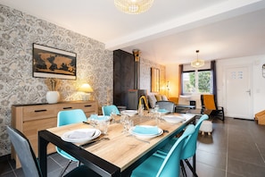 A dining area with a wooden table set for four, blue chairs, a world map on the wall, and a fireplace.