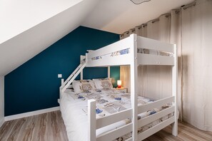 Un lit superposé avec une structure blanche, un mur d’accent de couleur turquoise et un plancher en bois.