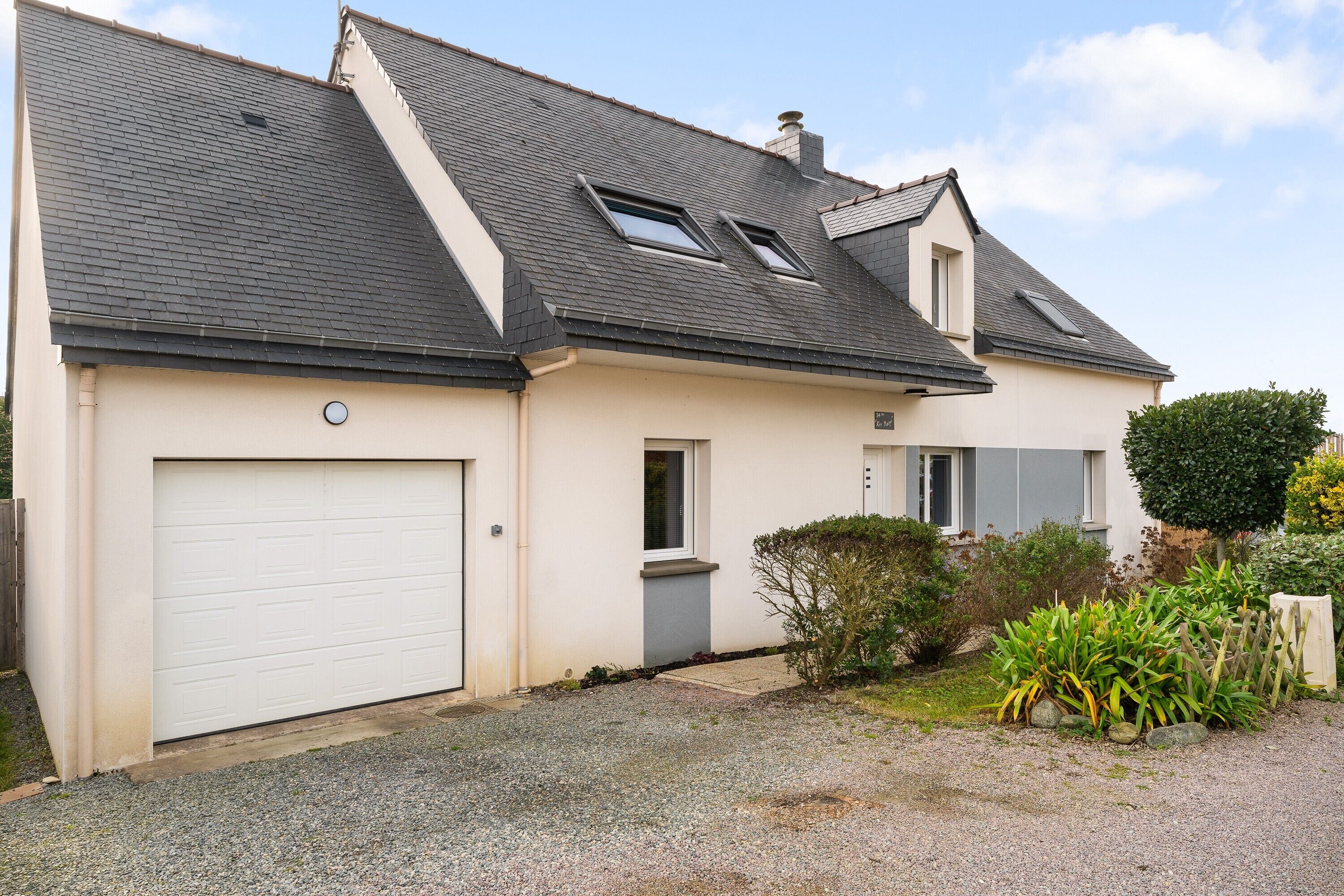 A two-story house with a garage, two skylights, and a small garden.