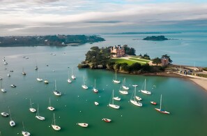 A coastal view with a castle-like structure surrounded by water and boats. - Holiday Home 'Ker Marjac' 3 Stars, Wheelchair Accessible, Hot Tub, Wood Stove, Private Garden & Wi-Fi (Dinard)